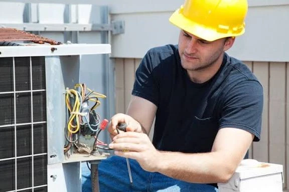 Technician working on wiring inside an open HVAC unit